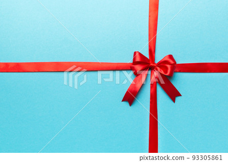 Top view of Red ribbon rolled and red bow isolated on colored background. Flat lay with copy space 93305861