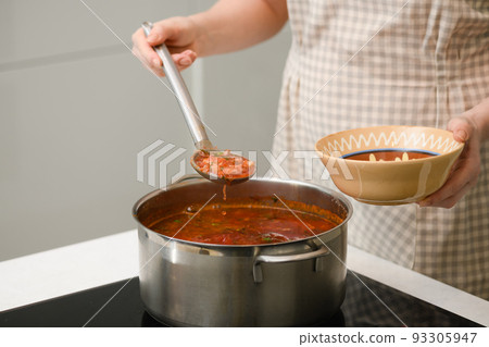 A woman pours freshly prepared Ukrainian borscht onto a plate. A woman pours freshly prepared Ukrainian borscht onto a plate. 93305947