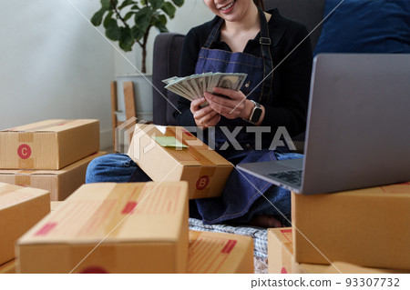 Asian SME business woman holding money and happy. online shopping concept Asian SME business woman holding money and happy. online shopping concept 93307732