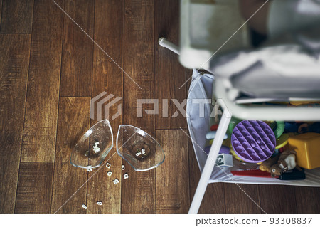 A baby on a high chair, dropped a cup of noodle soup on the wooden floor. The concept of accidents in the kitchen is dangerous for small children in the house. High quality photo 93308837