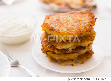 Potato pancakes with sour cream on white plate 93310248