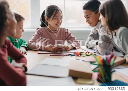 Happy Multicultural School Children Using Phone During Break In Classroom 93310885