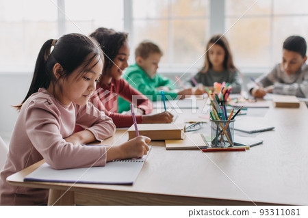 Asian Schoolgirl Taking Notes Learning Sitting In Modern Classroom 93311081