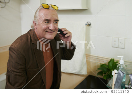 Positive elderly man shaving face when getting g ready in the morning Positive elderly man shaving face when getting g ready in the morning 93311540