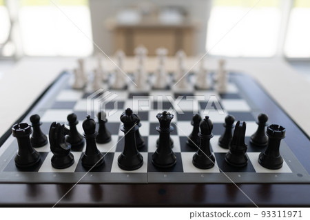 New chess board with chess pieces on table for game. 93311971