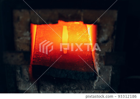 Blacksmith forge oven with hot flame. Smith heating iron piece of steel in fire of red-hot forge. Blacksmith forge oven with hot flame. Smith heating iron piece of steel in fire of red-hot forge. 93312186