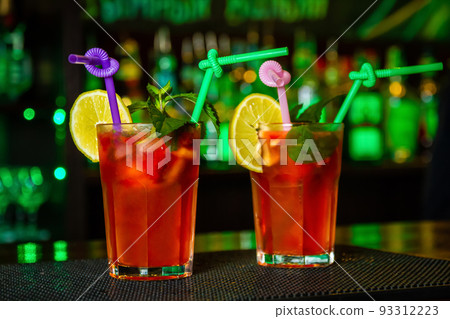 Red Alcoholic cocktails decorated with slices of lemon on the bar counter 93312223