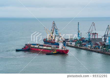 container ship is moored with the help of tugboats to a cargo berth 93312291