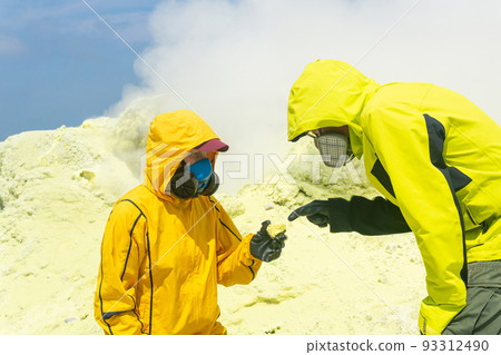 volcanologists on the slope of the volcano examines samples of minerals against the backdrop of smoking sulfur fumaroles 93312490