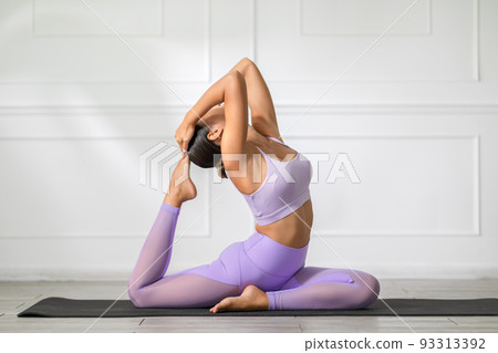 Side view of Asian woman wearing purple sportwear doing Yoga exercise,Yoga Child pose or Balasana. Calm of healthy young woman breathing and meditation with yoga at home. Exercise for wellness life 93313392