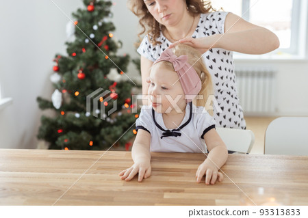 Mother fixing her daughter's cochlear implant hearing aid - deafness and diversity concept. Innovative technologies in treatment of deafness 93313833