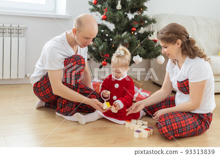 Baby child with hearing aid and cochlear implant having fun with parents in christmas room. Deaf , diversity and health and diversity 93313839