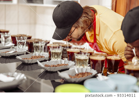 Male employee tasting coffee and smelling the aroma of many cups Male employee tasting coffee and smelling the aroma of many cups 93314011