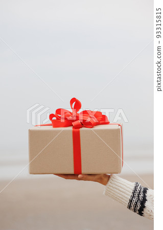 woman in a Santa Claus hat with a gift box in her hands smiles. a happy European woman carries a gift for New Year or Christmas. 93315815