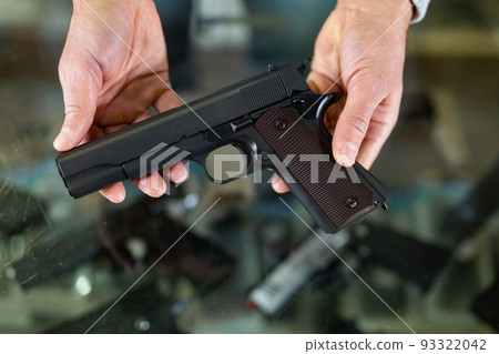 Hands holding pistol over showcase 93322042