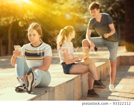 Teen girl with phone on summer city street 93322112