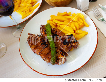 traditional spanish fried pettitoe with fries served on black plate on wooden table 93322786