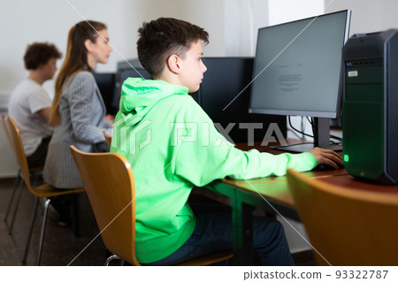 Schoolboy using computer at lesson, teacher teaching pupils in class room 93322787