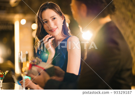 Bearded man giving a present to a beautiful woman at a bar Bearded man giving a present to a beautiful woman at a bar 93329187