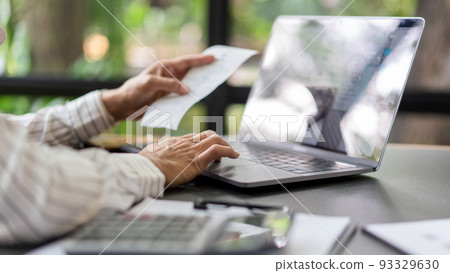 Business concept, Businesswoman holds receipt to checking expense of project and typing on laptop Business concept, Businesswoman holds receipt to checking expense of project and typing on laptop 93329630
