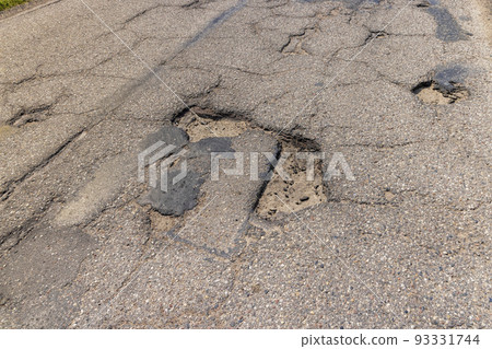 An old paved road with a lot of holes and damage An old paved road with a lot of holes and damage 93331744