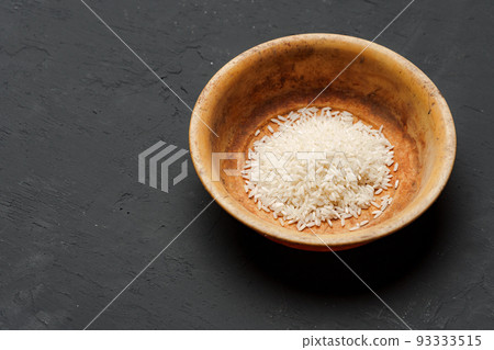 Heap of dry rice in a bowl on black background, lack of food, hunger concept 93333515