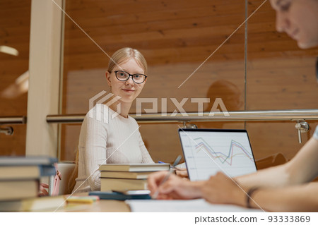Two friends students with laptop and books studying in University Library 93333869