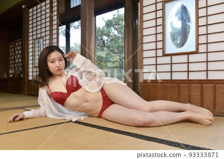 一位穿著粉色內衣的年輕女子坐在一座古老民居的日式房間裡 93333871