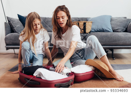 Mother and daughter going on trip pack suitcase 93334693