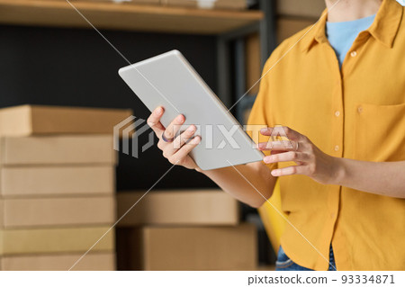 Close-up of woman using digital tablet to check track number while working in warehouse Close-up of woman using digital tablet to check track number while working in warehouse 93334871