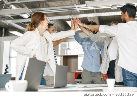 Happy group of multi ethnic coworkers stacked hands together as concept of corporate unity 93335359