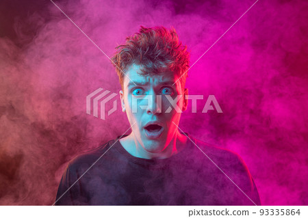 Shouting excited young man with bright emotions isolated over pink background with smoke. Concept of mental health, art, human emotions 93335864