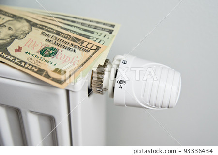 Heating radiator with dollar bills closeup, Energy crisis concept, Rising costs in private households for gas bill due to inflation and war 93336434