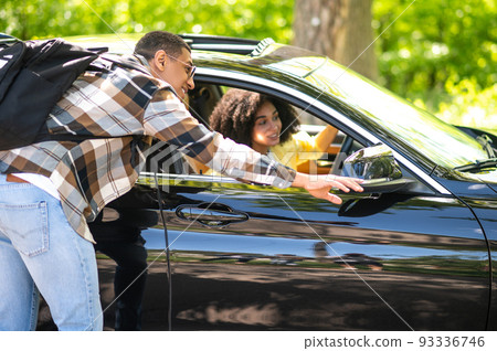 Young man on the road flirting with a female driver while asking the way Young man on the road flirting with a female driver while asking the way 93336746
