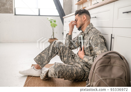 Dejected serviceman pressing the photograph against his chest 93336972