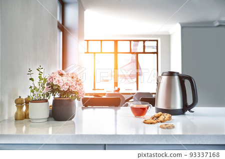 Breakfast scene at sunny morning. Transparent black tea mug with biscuit on kitchen table Breakfast scene at sunny morning. Transparent black tea mug with biscuit on kitchen table 93337168