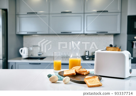 Portion of toasts on a wooden board with orange juice. Breakfast is served on a table with light blue napkin. Portion of toasts on a wooden board with orange juice. Breakfast is served on a table with light blue napkin. 93337714