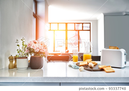 Portion of toasts on a wooden board with orange juice. Breakfast is served on a table with light blue napkin. 93337748