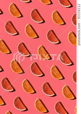 Pattern made of colorful candied fruits orange lemon on coral background. Flat lay. Minimal concept 93338112