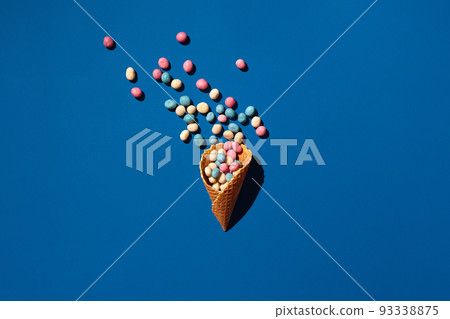 An image of a heap of dragee sweets that is sprinkled from a waffle cone An image of a heap of dragee sweets that is sprinkled from a waffle cone 93338875