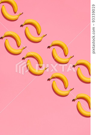 Pattern composition of a pair of bananas lying next to a pink background , top view 93339019