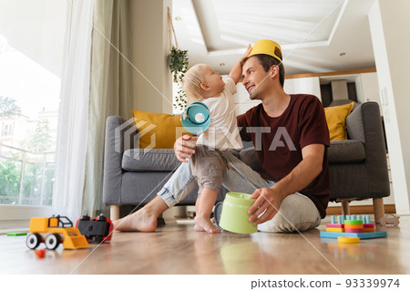 Father and son having fun together playing games and toys on floor in living-room 93339974