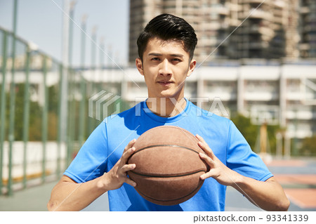 young asian male player holding a basketball looking at camera 93341339