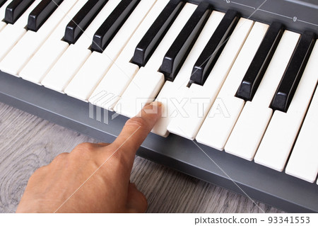 Finger presses the white piano key closeup Finger presses the white piano key closeup 93341553
