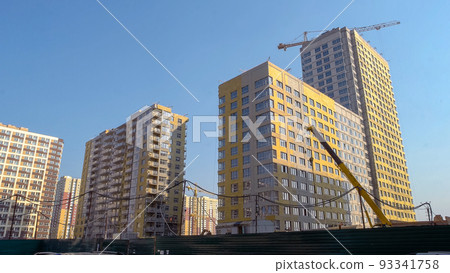 Many high-rise buildings and yellow construction crane. Blus sky background. 93341758