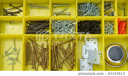 Various metal screws in separate yellow plastic containers. 93343613