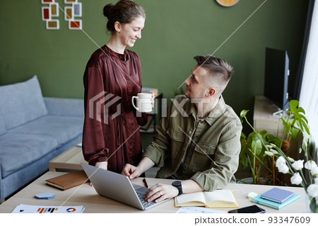 Woman bringing coffee for her busy man 93347609