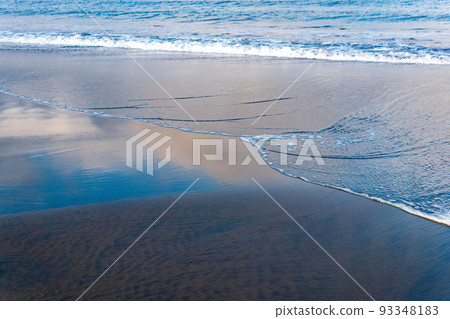 ocean beach with black volcanic sand, the sky is reflected in the rolled back wave of the surf ocean beach with black volcanic sand, the sky is reflected in the rolled back wave of the surf 93348183