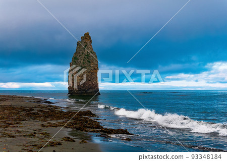 seascape of Kunashir, ocean shore with a huge vertical rock in the water and a wild beach with algae thrown out by the sea seascape of Kunashir, ocean shore with a huge vertical rock in the water and a wild beach with algae thrown out by the sea 93348184
