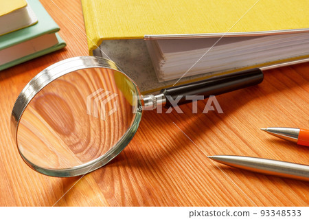 Office table with folder and magnifying glass. HR investigation concept. 93348533